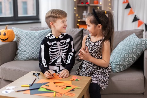 Two young kids doing a Halloween craft together.