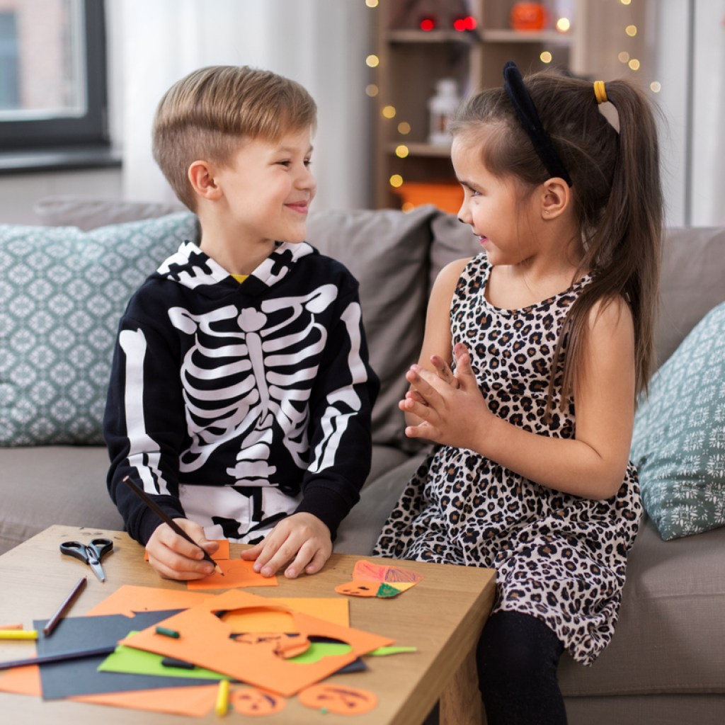 Two young kids doing a Halloween craft together.