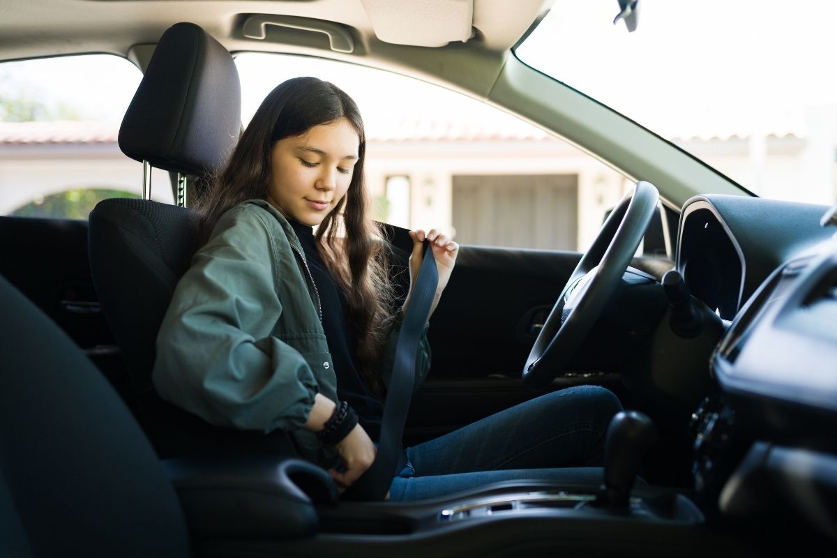 Teen girl driver fastening her seatbelt