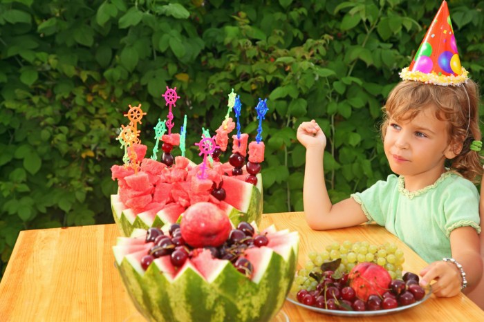 Little girl having a healthy fruit cake at her birthday party