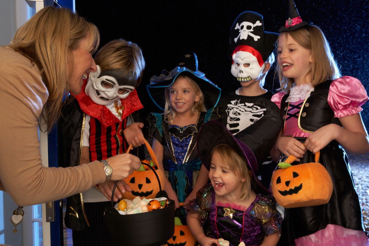 Kids in various costumes receiving trick or treat candy