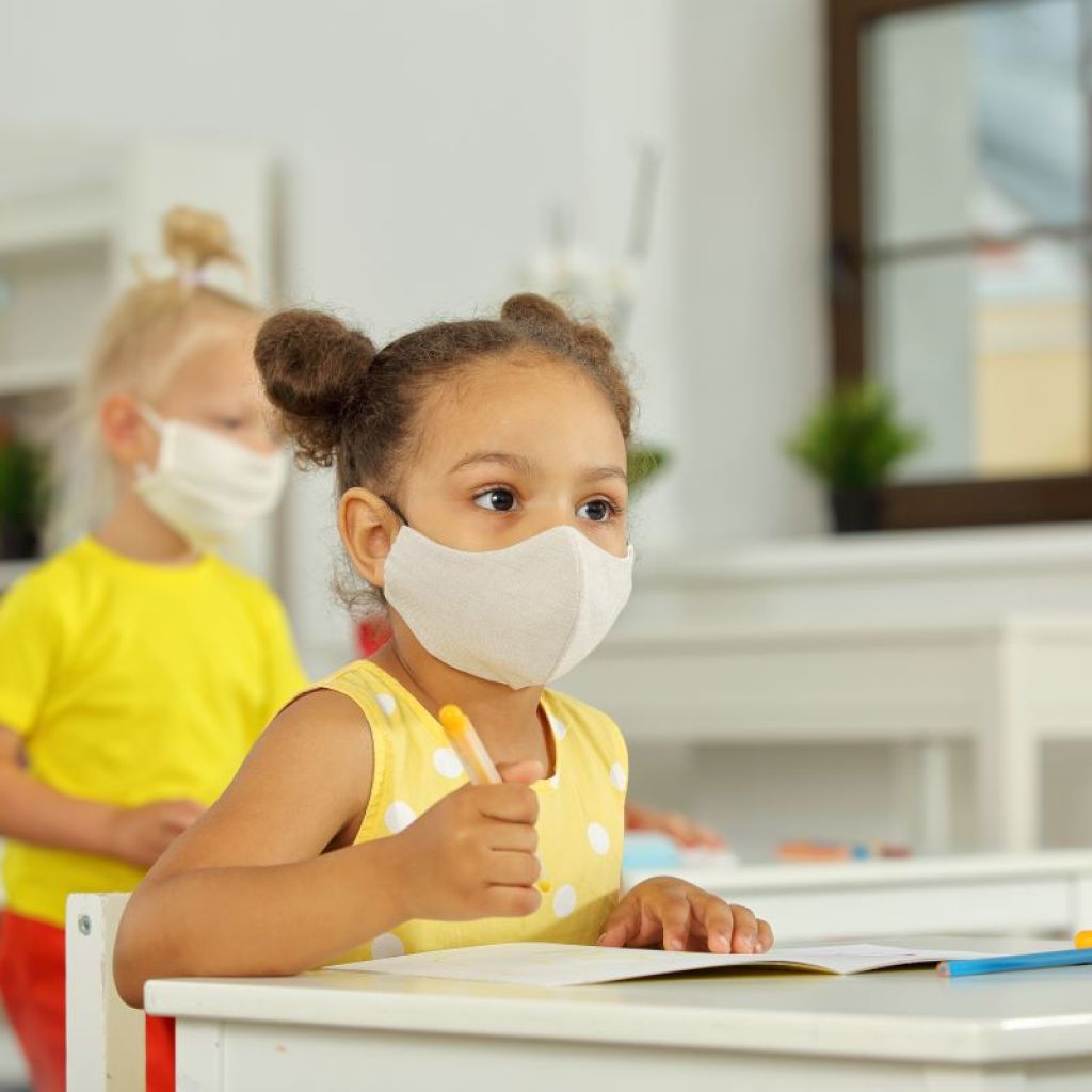 Little girl sitting in class wearing a mask