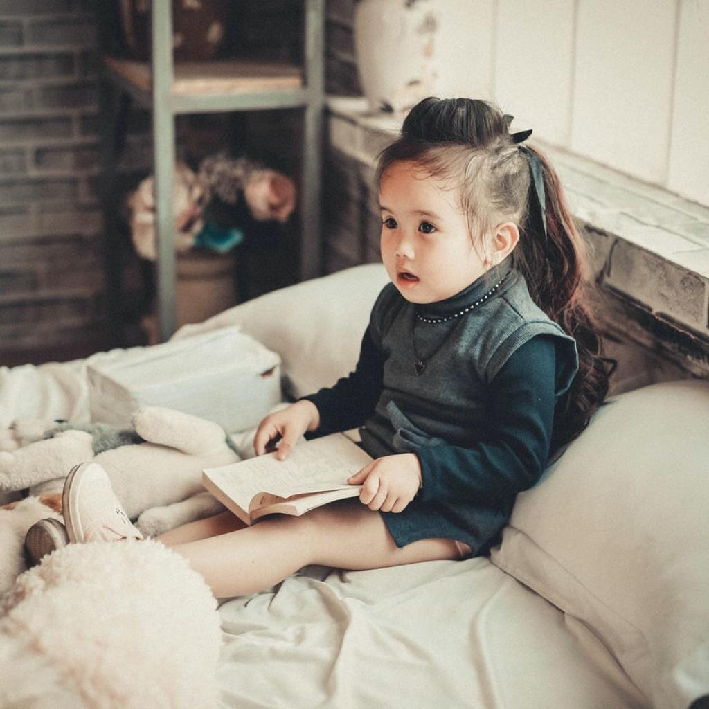Little girl sitting up in bed with a book