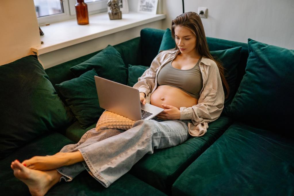 Pregnant woman relaxing on a couch with her laptop