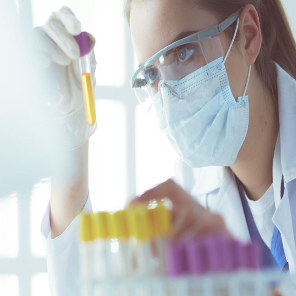 scientist holding dropper over test tubes