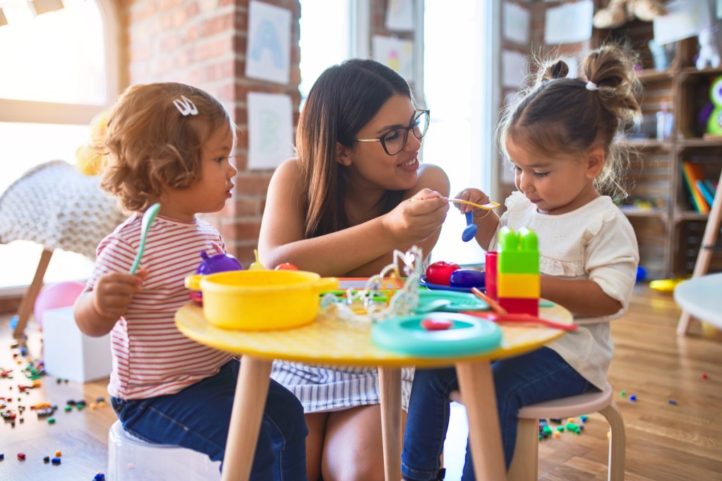 A nanny feeding toddlers in her care