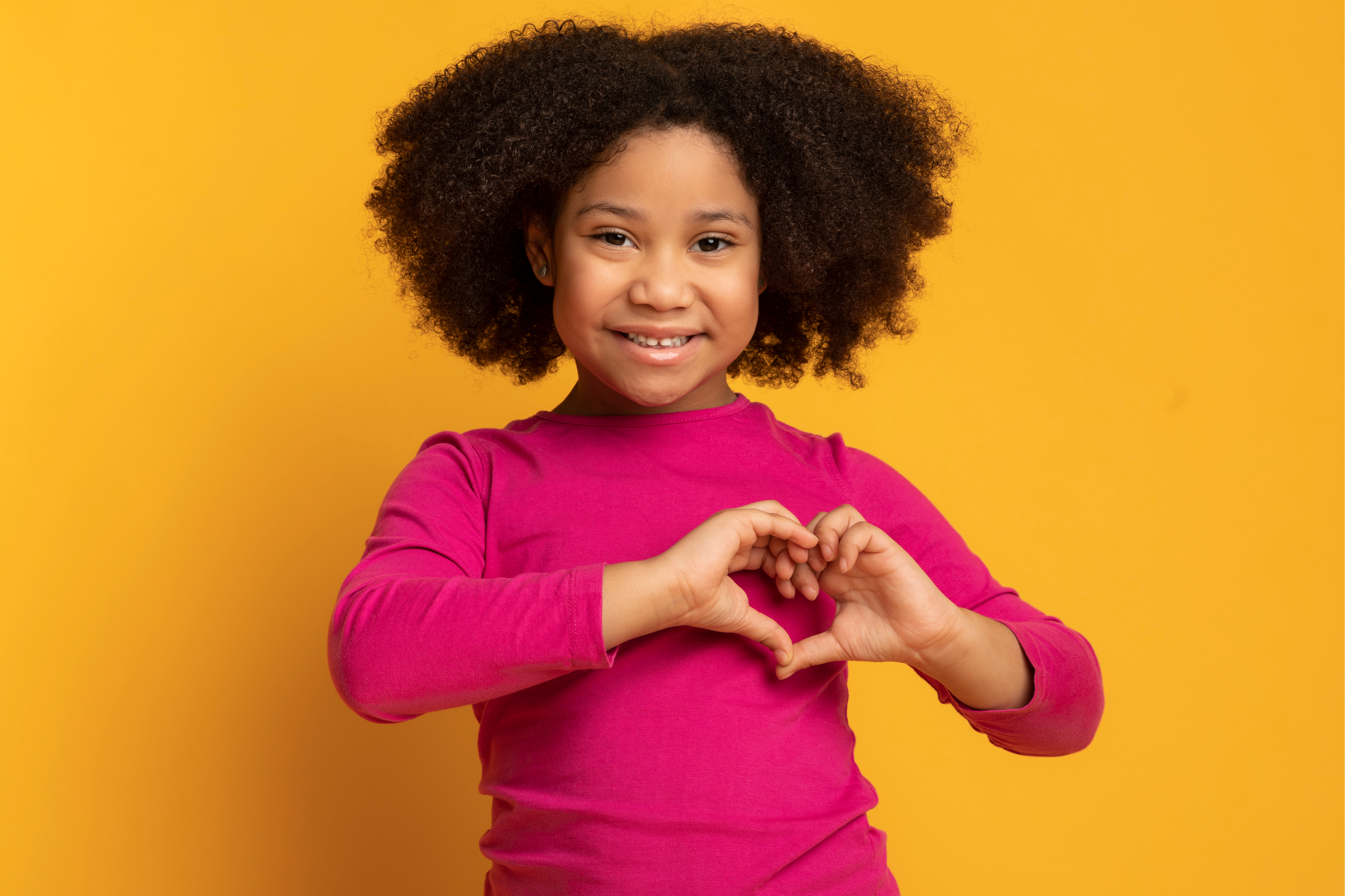 A girl making a heart with her hands.