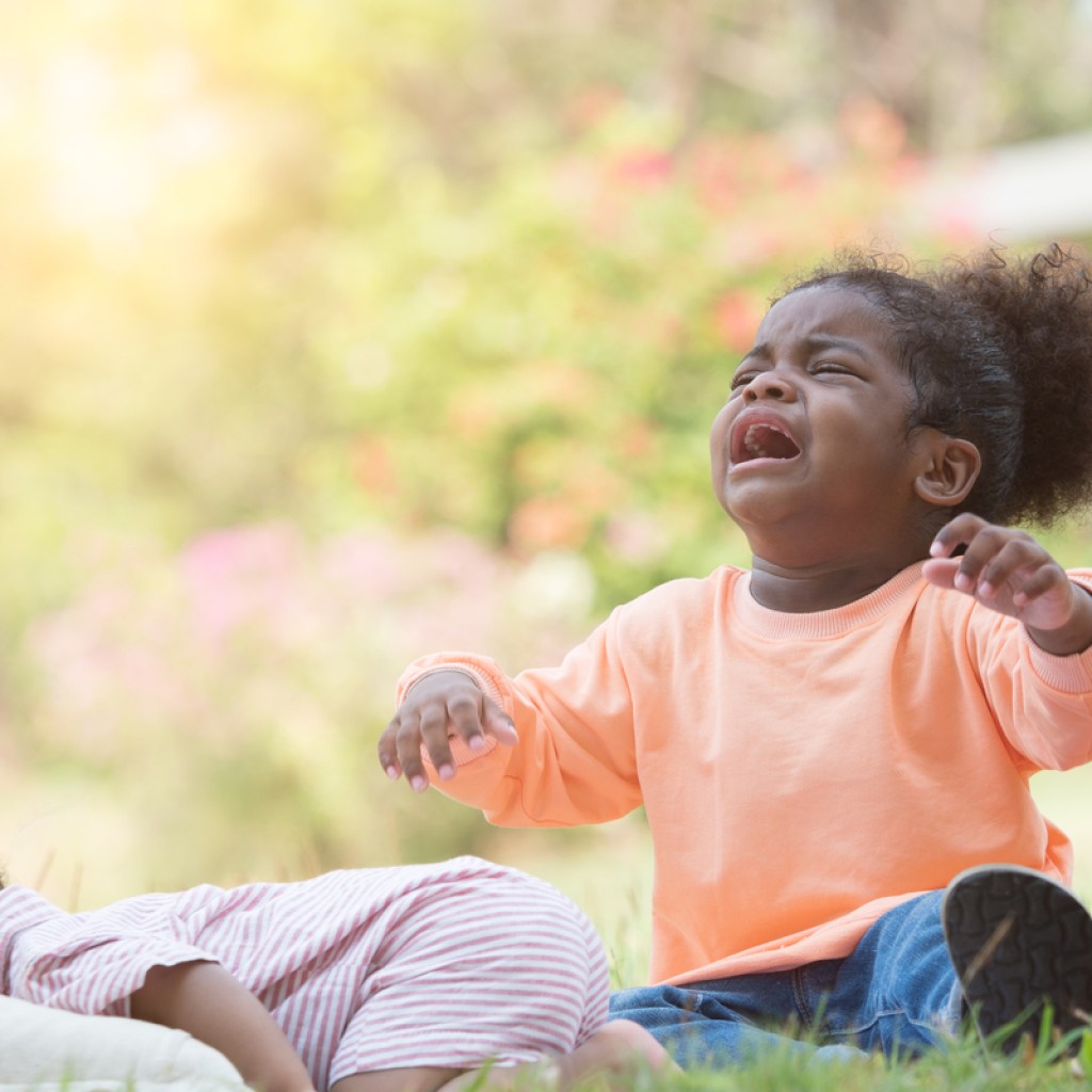 A toddler throwing a tantrum outside.