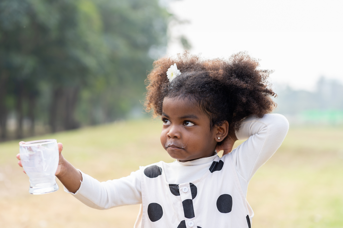 A little girl who finished drinking a glass of milk.