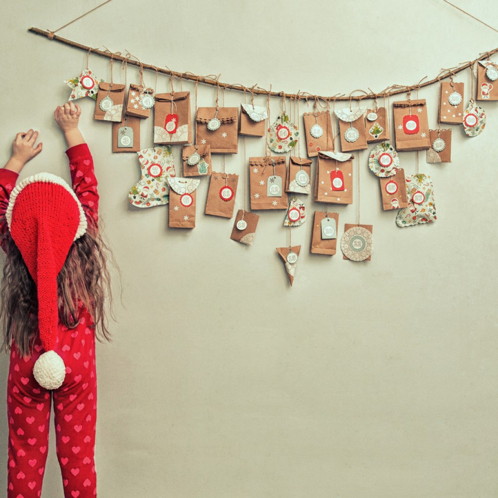 little girl reaching for a hanging advent calendar