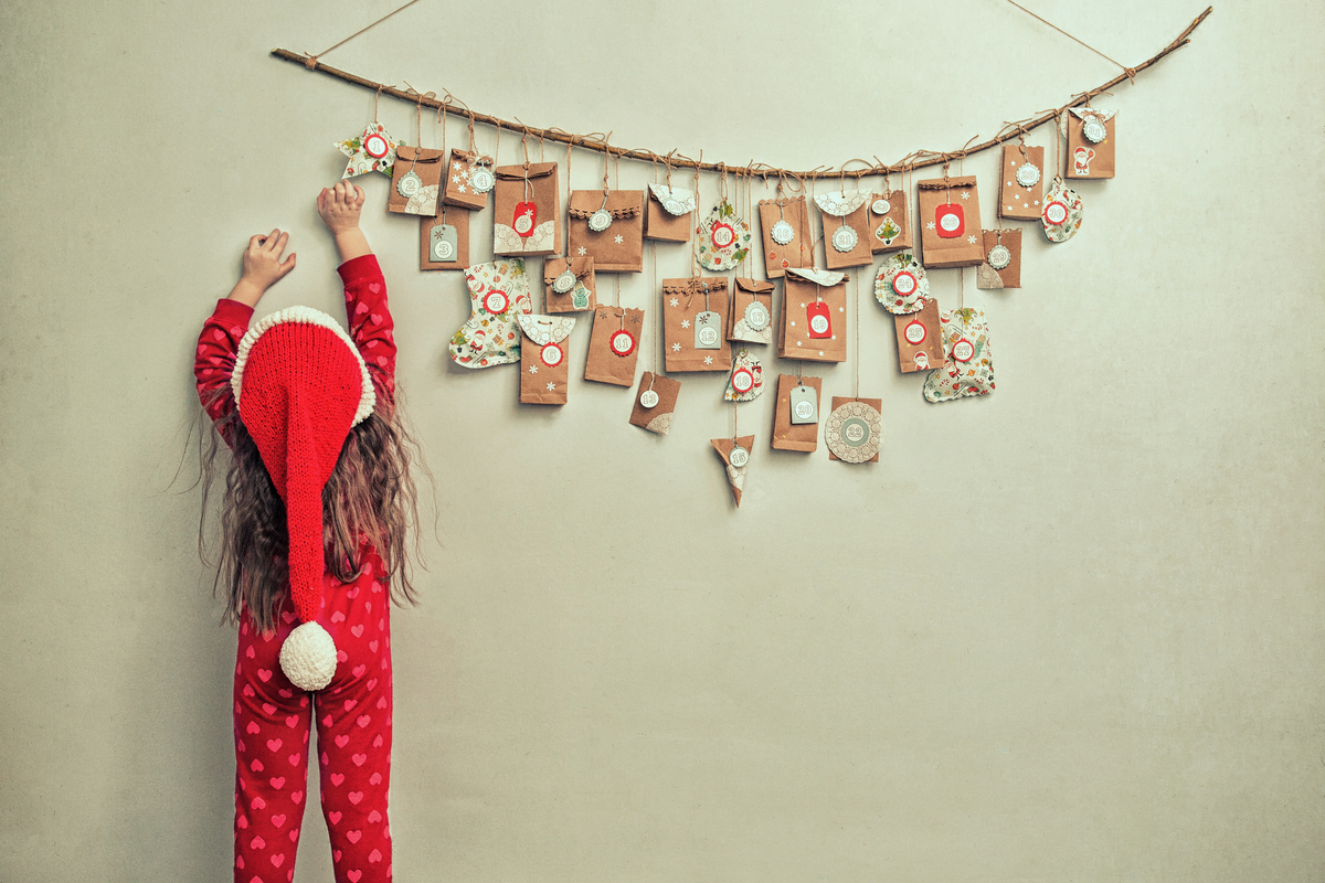 little girl reaching for a hanging advent calendar