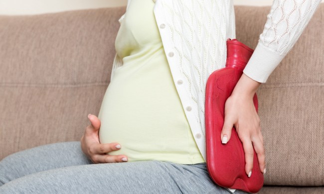Pregnant woman using heating pad hot water bottle