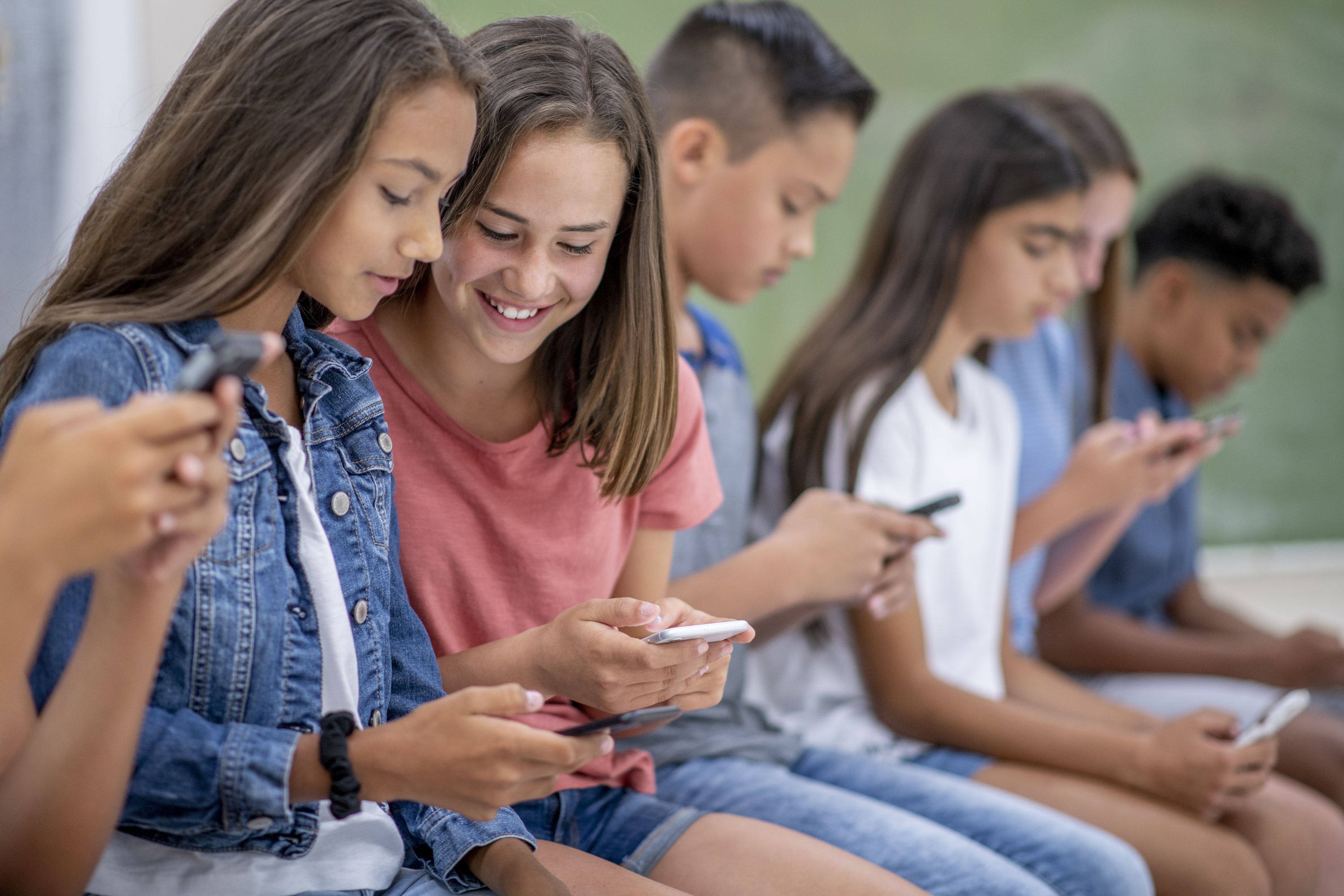 A group of teens on their phones.