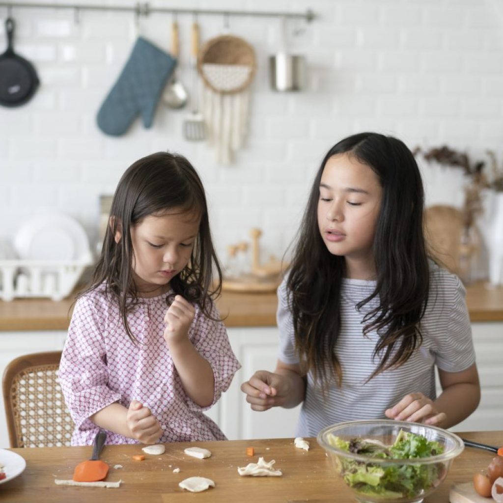 Two children are making a snack in the kitchen.