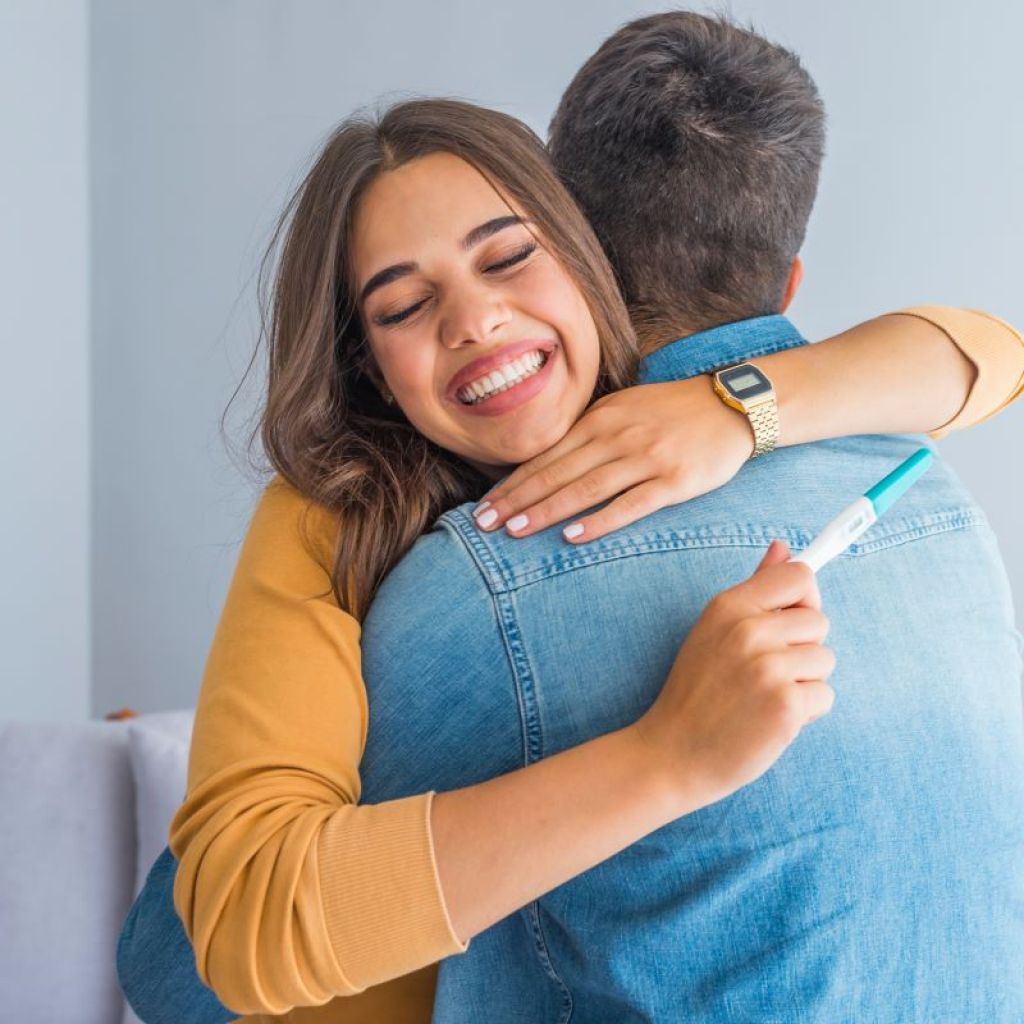 Couple hugging after looking at pregnancy test result
