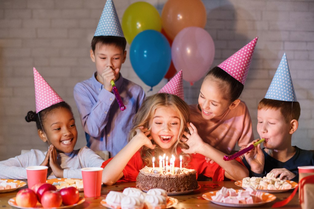 Excited kids surrounding a birthday cake