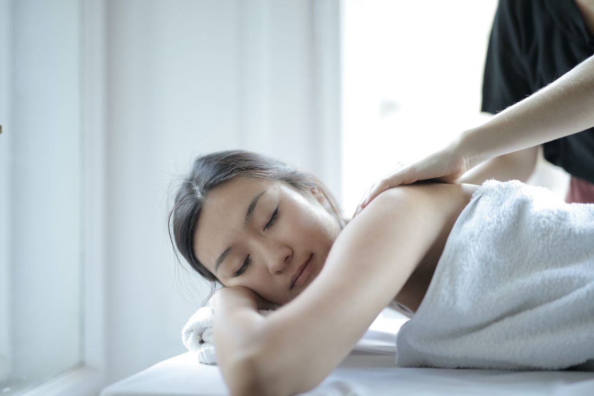 A lady lays face down on massage table getting a massage
