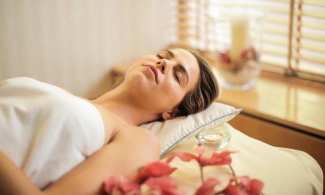 A lady is laying on a massage table with a pillow