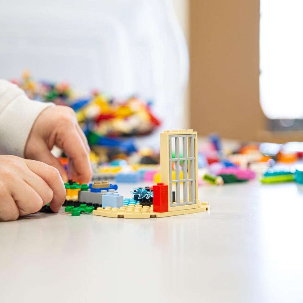 A child's hands playing with LEGO.