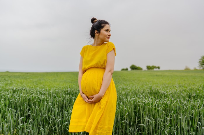 Pregnant woman in yellow dress standing in field