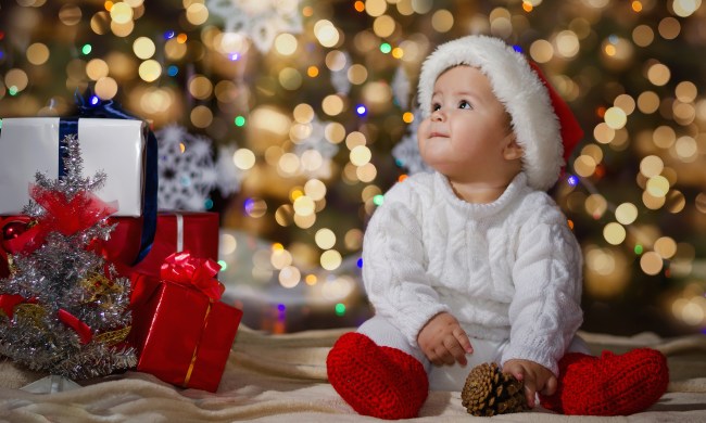 Happy baby by the tree surrounded by holiday magic