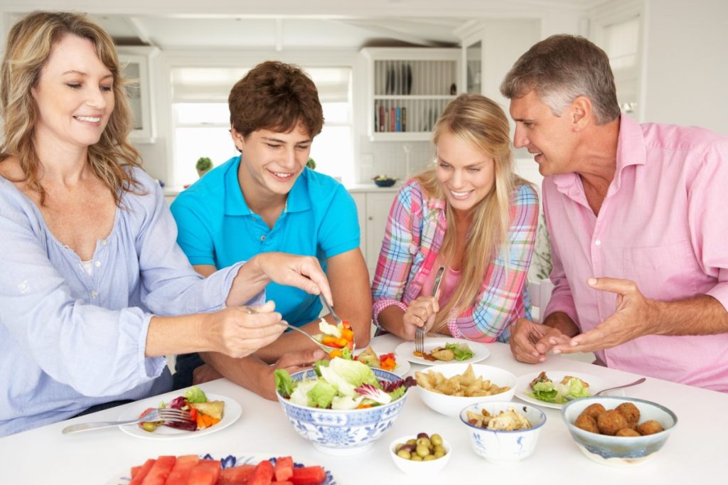 Teens eating dinner with their parents.