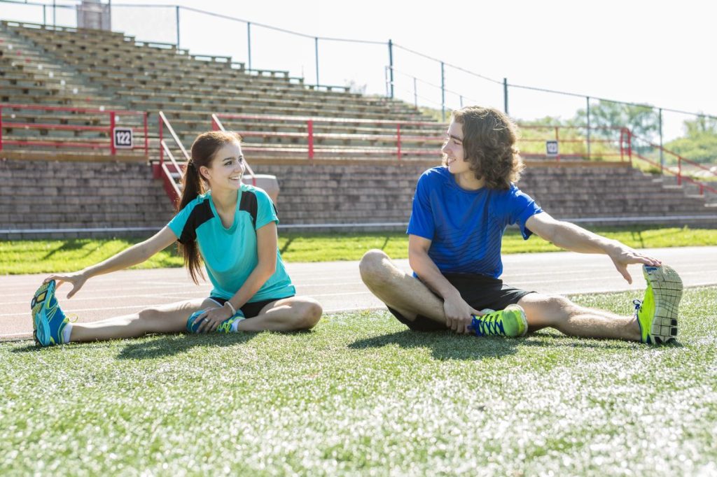 A couple of teenagers stretching before being active.