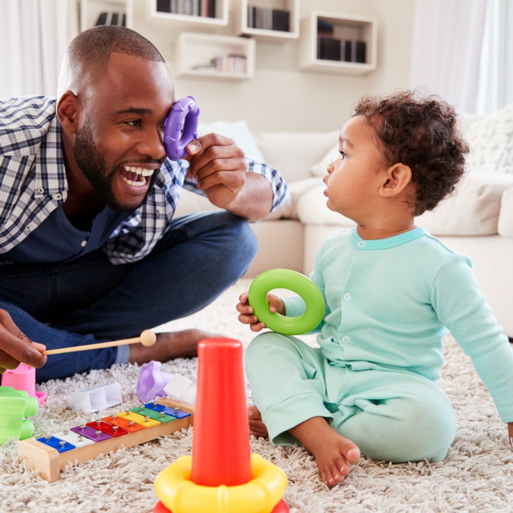 Toddler and dad having fun playing with toys on the floor