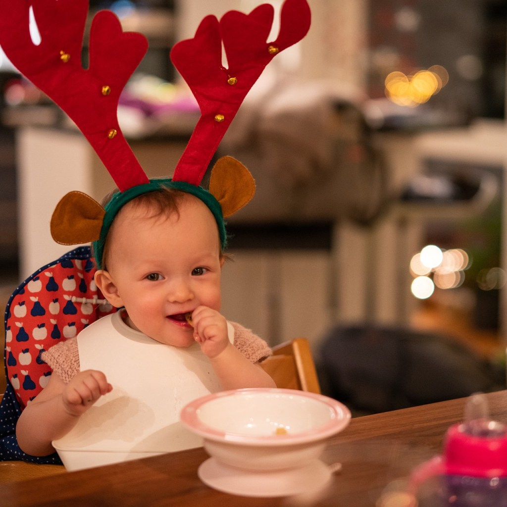Baby eating in a reindeer hat
