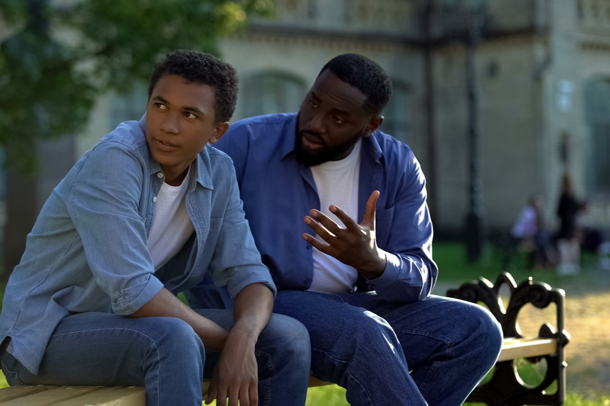 father and teen having a talk on a bench