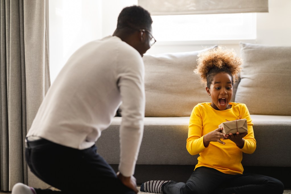 Girl is excited about getting a Christmas present from her father.