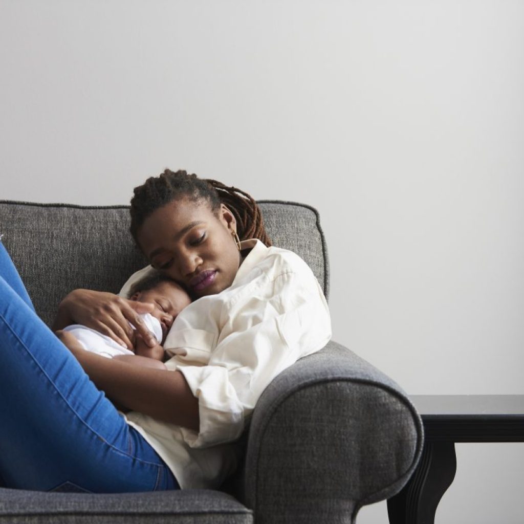 Mother cuddling baby while resting on the couch
