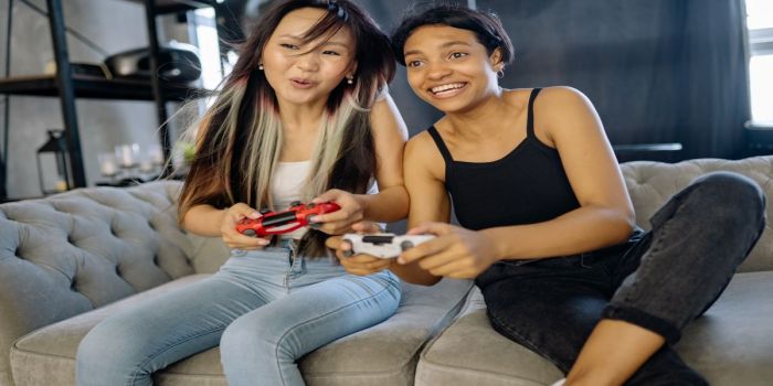 girls playing video games while sitting on couch