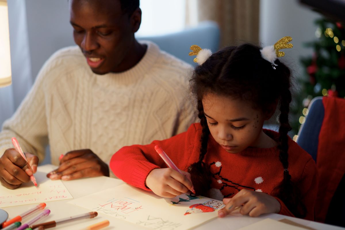 Dad and daughter writing letters to Santa Claus.