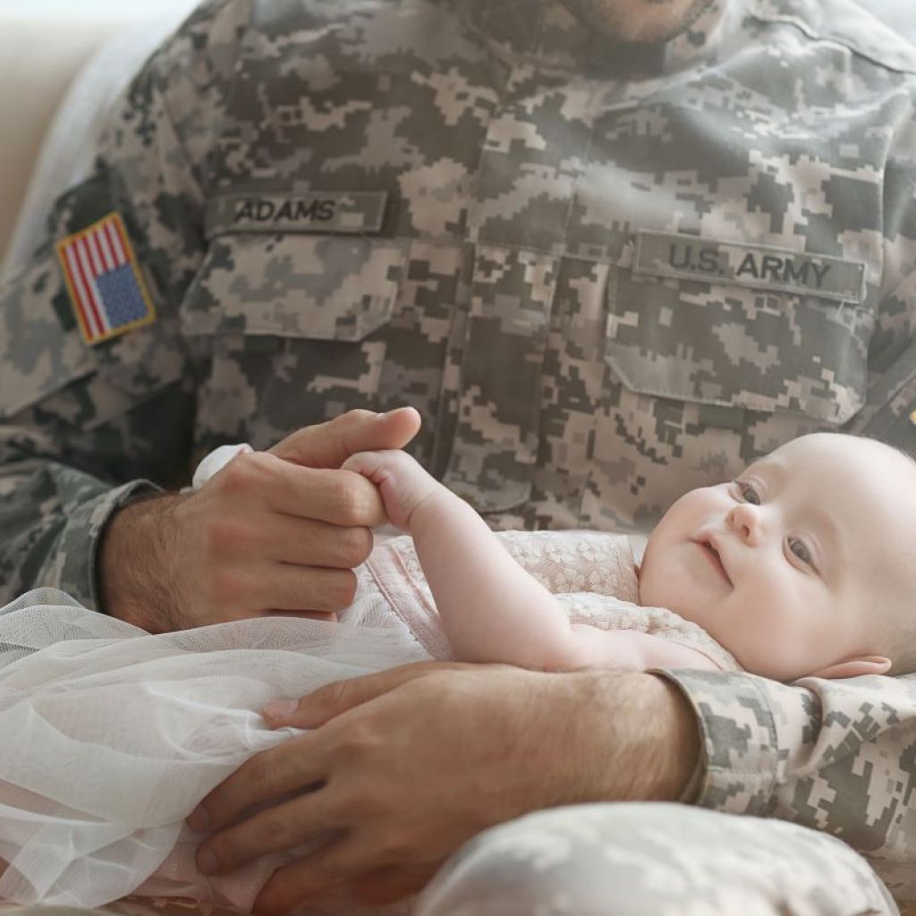 Military dad in uniform holding baby girl