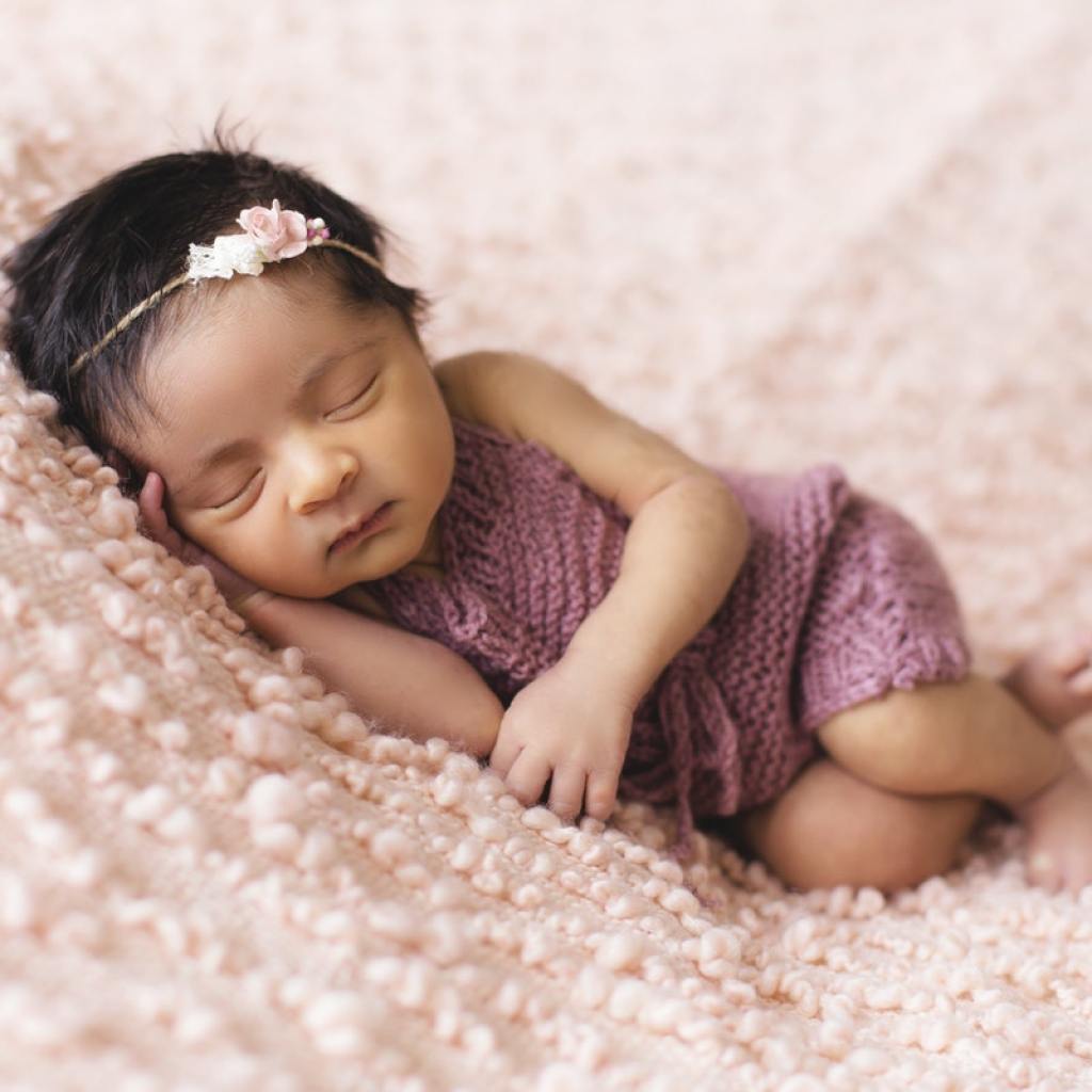 Newborn girl sleeping on a pink blanket.