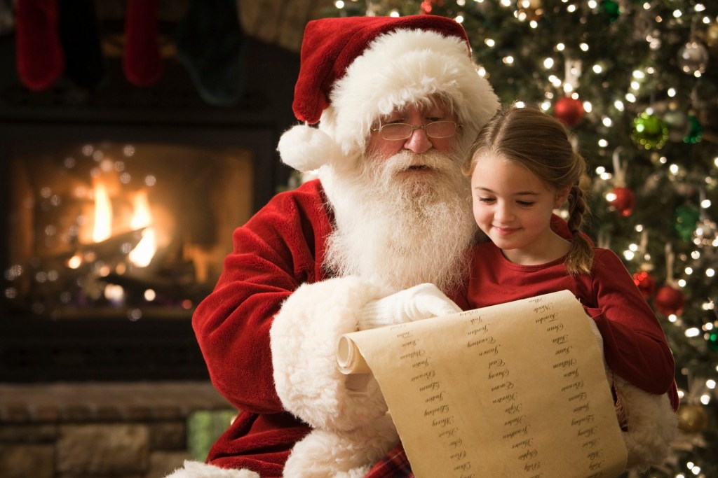 Santa sitting with a little girl going over the list