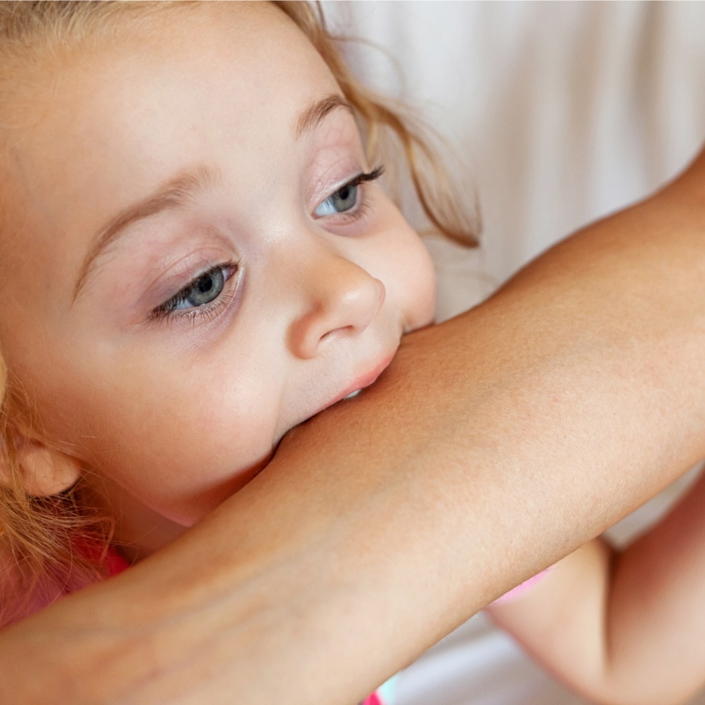 Toddler biting an adult arm