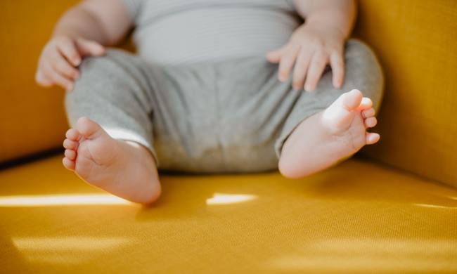 Toddler sitting down with toes pointing towards camera