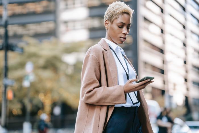 Black woman looking at phone on a city street