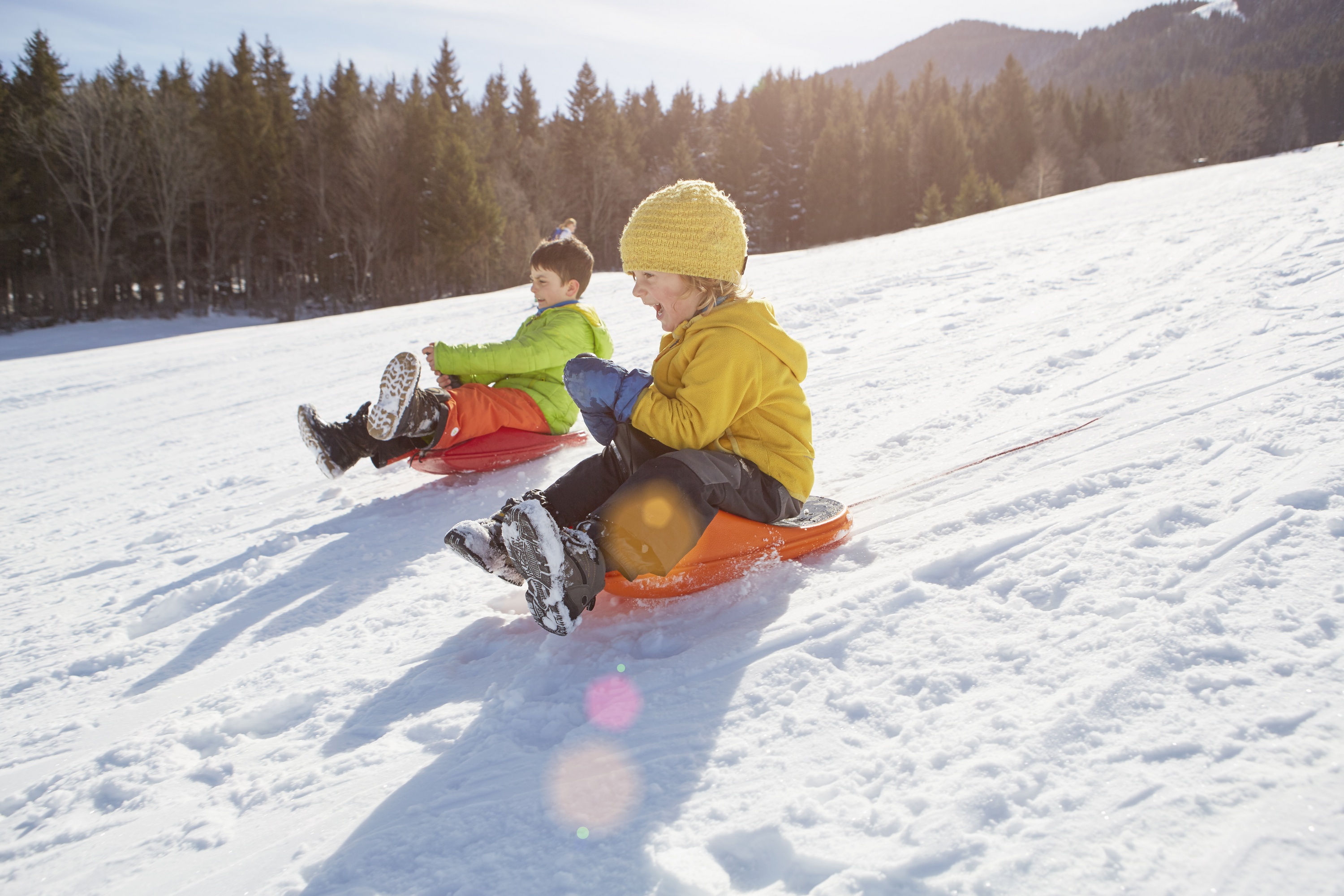 kids sledding down a snowy hill