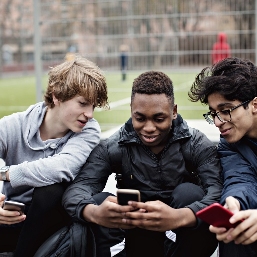 Three teen boys looking at phones.