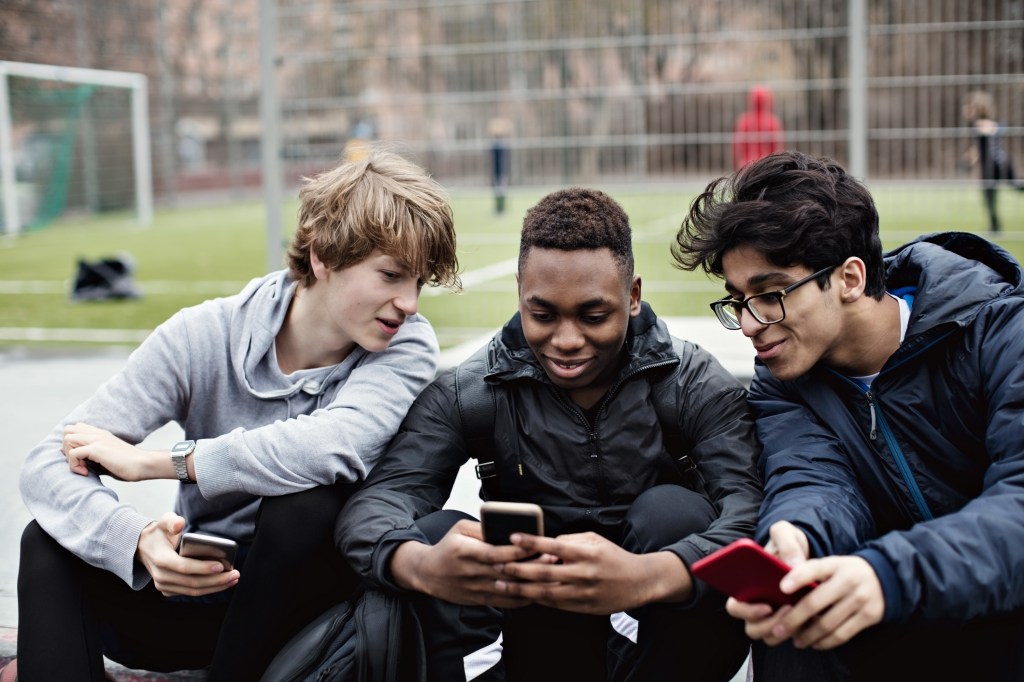 Three teen boys looking at phones.