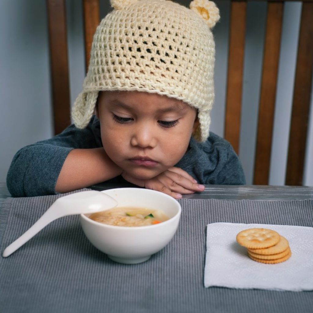 A toddler not wanting to eat their food.