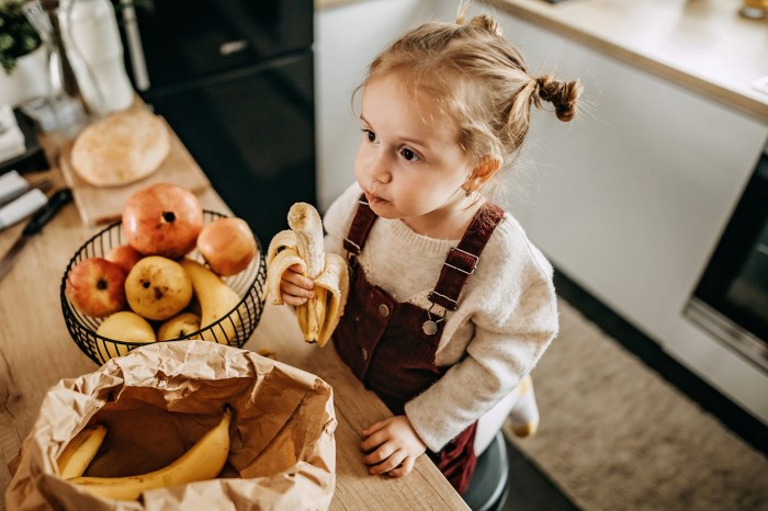Toddler girl eating fruit in the kitchen