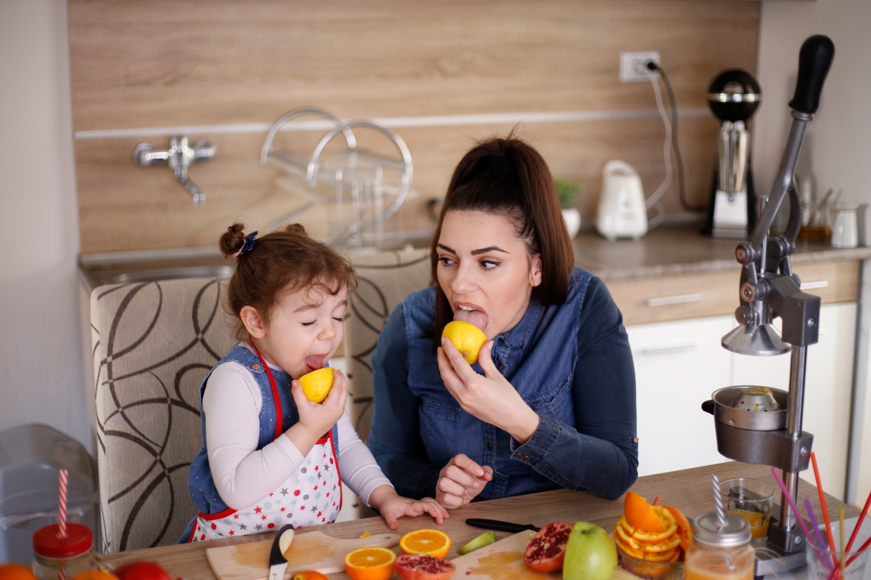 Mother and daughter making faces after licking raw lemons together