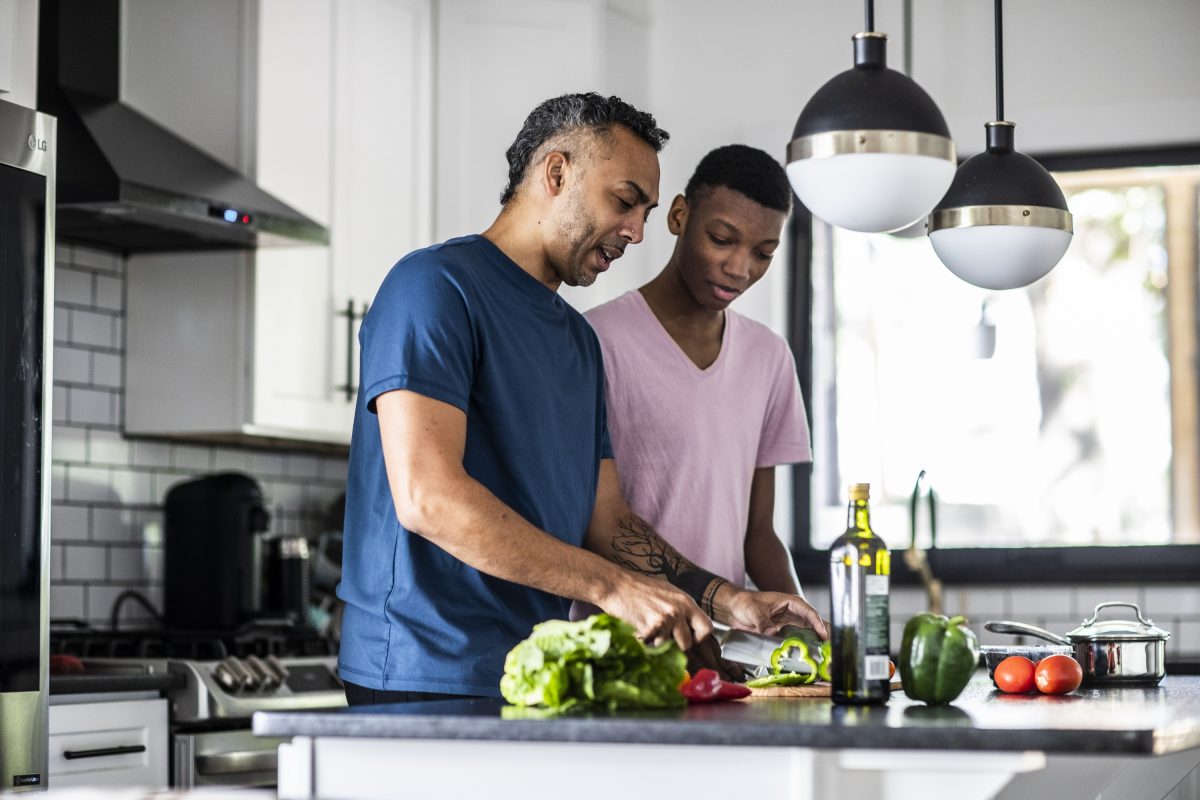 Parent and older child in the kitchen prepping dinner.