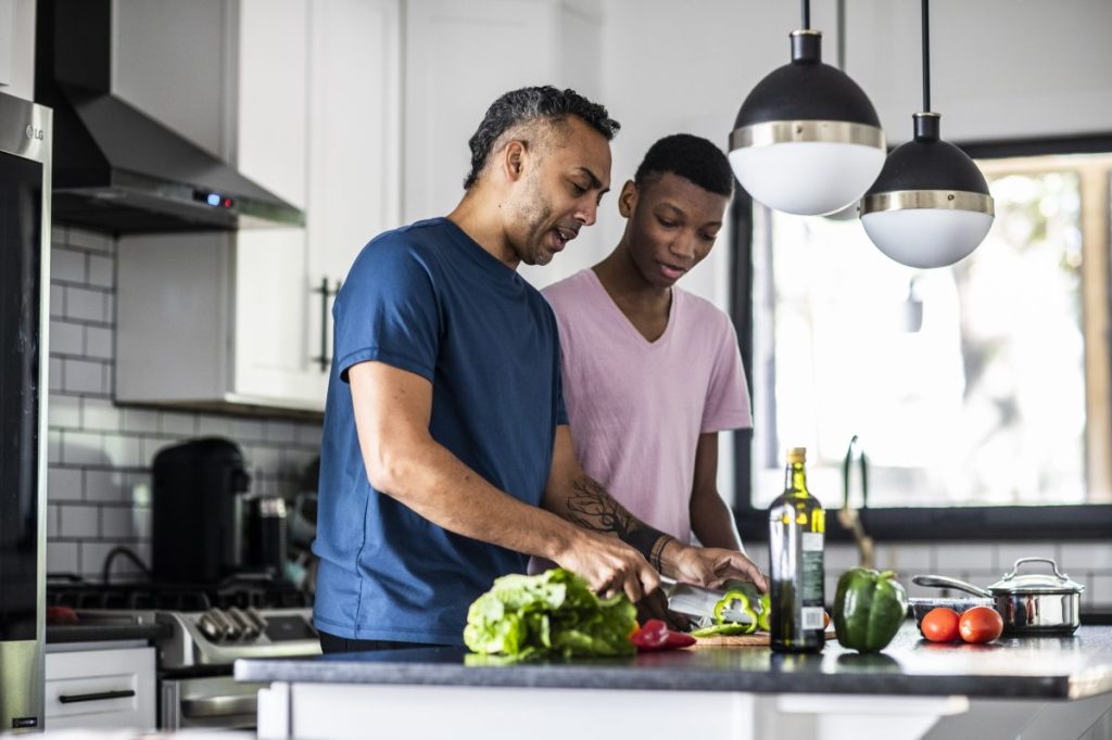 Parent and older child in the kitchen prepping dinner.