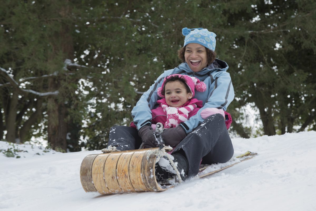 A mother and child sledding down a hill