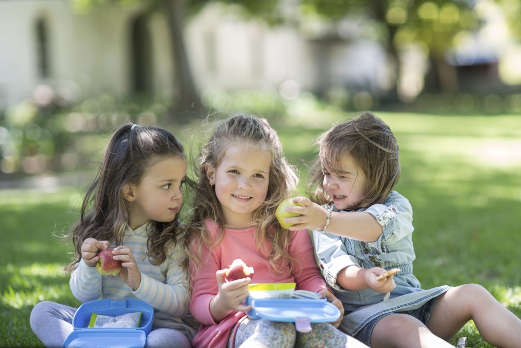 Toddler girls in a garden sharing lunch
